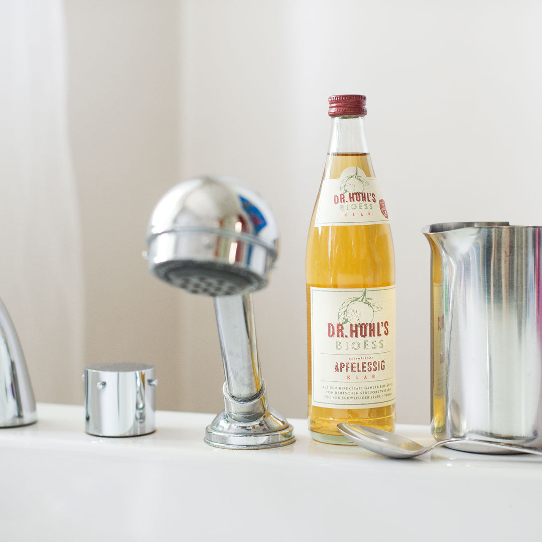Auf dem Badewannenrand steht eine Flasche Apfelessig