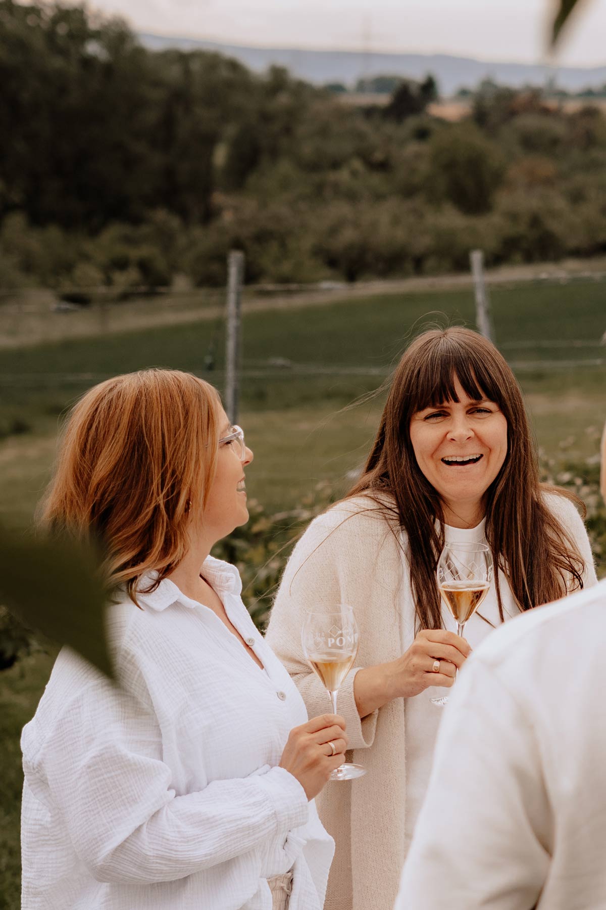 zwei frauen im grünen lachen in die kamera mit einem aperitif in der hand