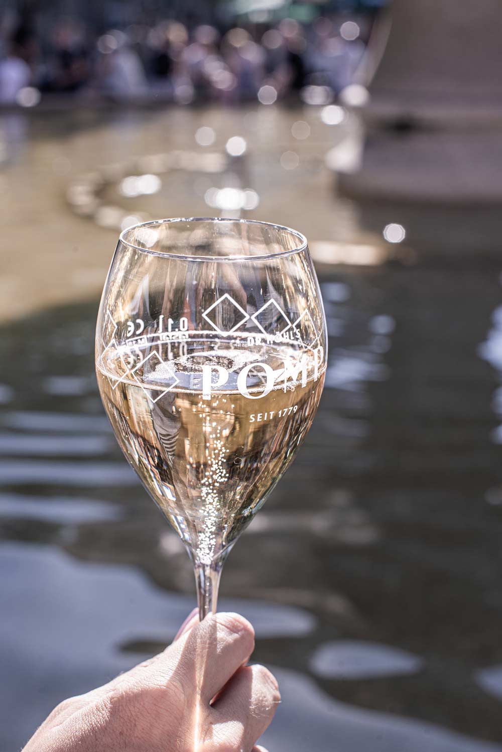 hand hält pomp champagnerglas gefüllt mit blanc