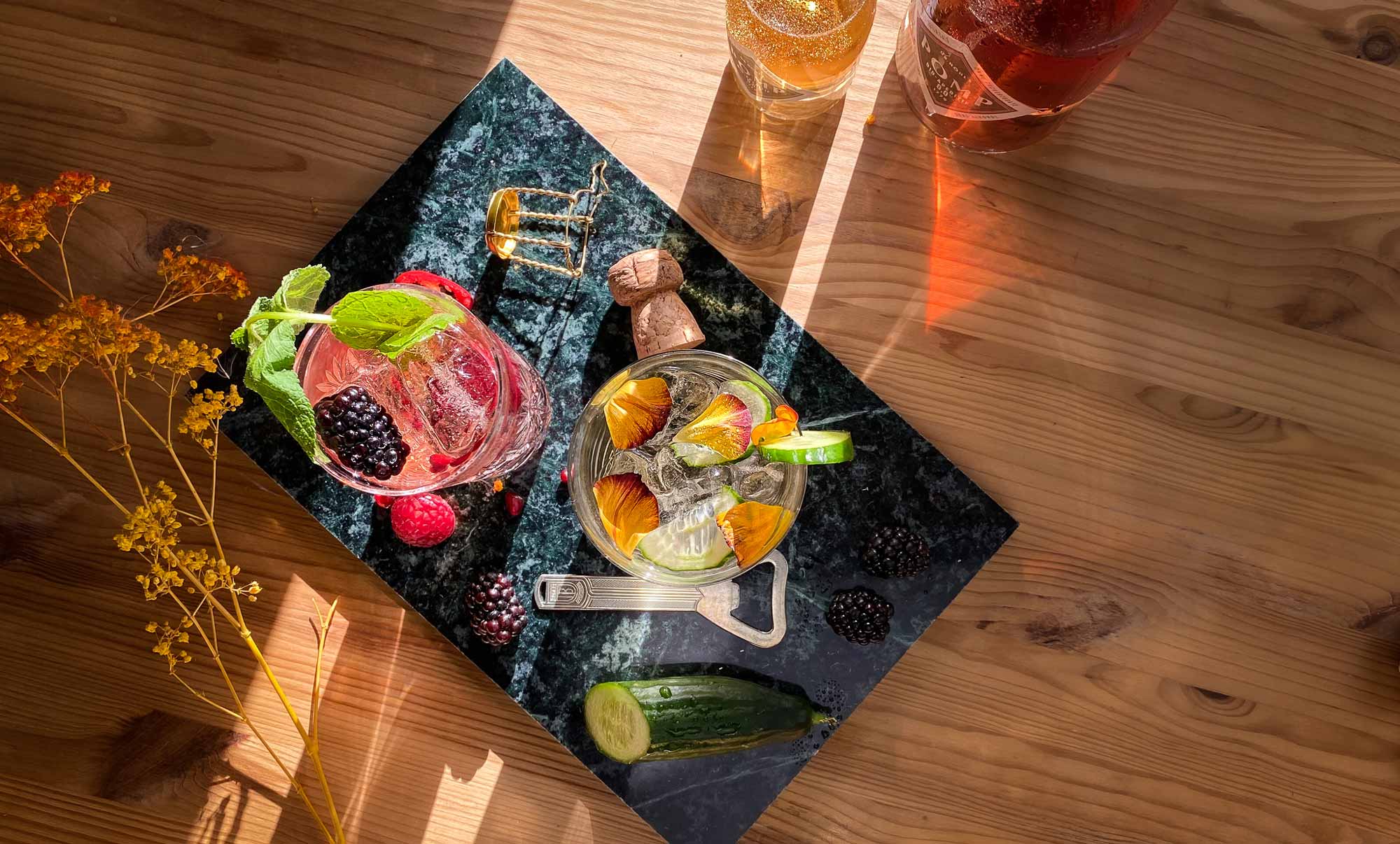 alkoholfreie drinks mit blüten und beeren dekoriert neben zwei flaschen bio filler