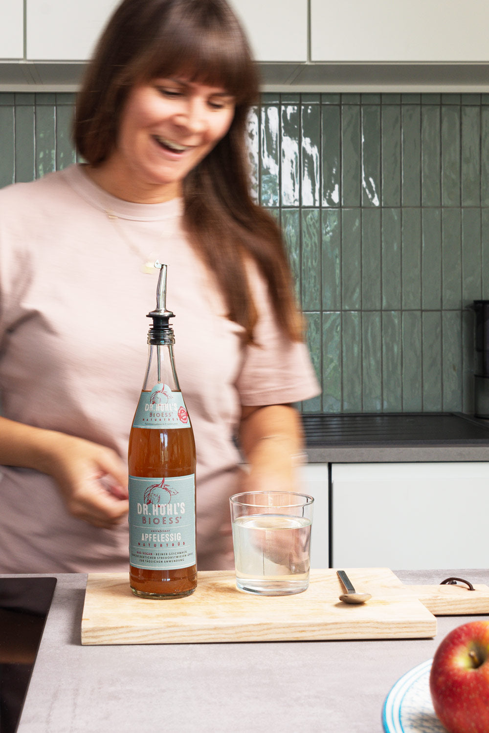 Anna greift zu einem Glas Apfelessig Wasser das auf der Küchenarbeitsfläche steht