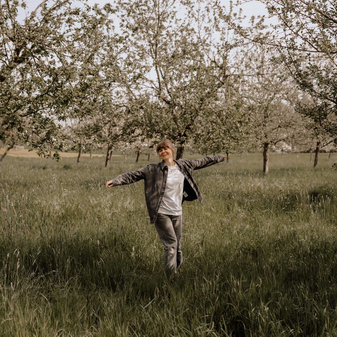Anna mit weit geöffneten Armen auf der Streuobstwiese