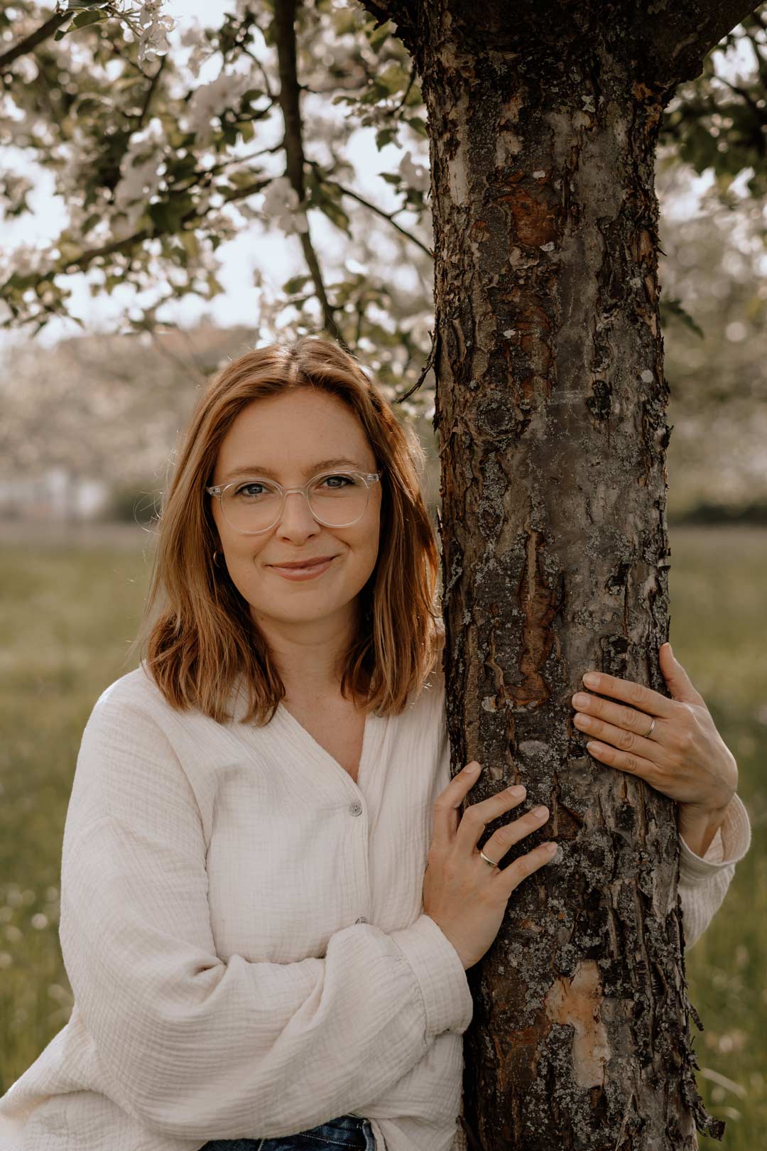 Christina umarmt den Stamm eines Apfelbaums auf unserer Streuobstwiese