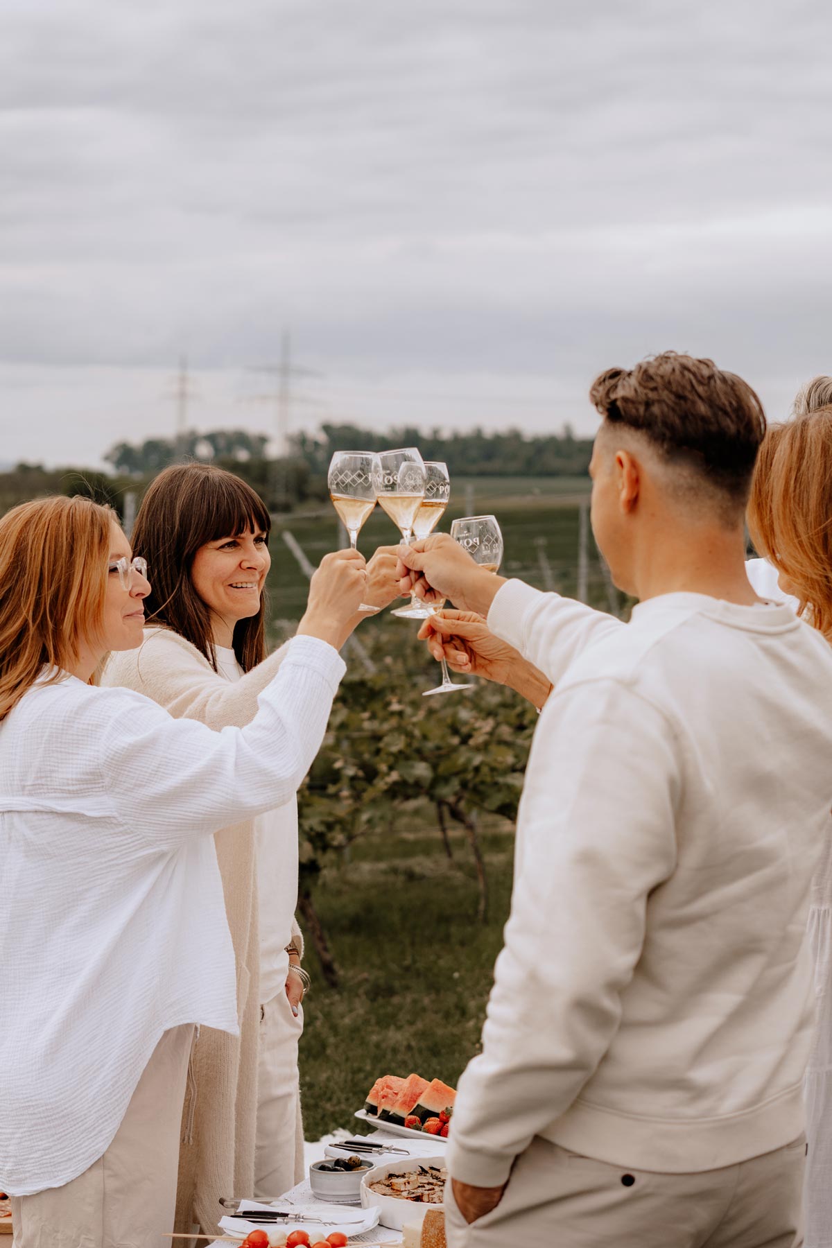 familie stößt mit pomp champagnergläsern bei einem picknick in den weinbergen an