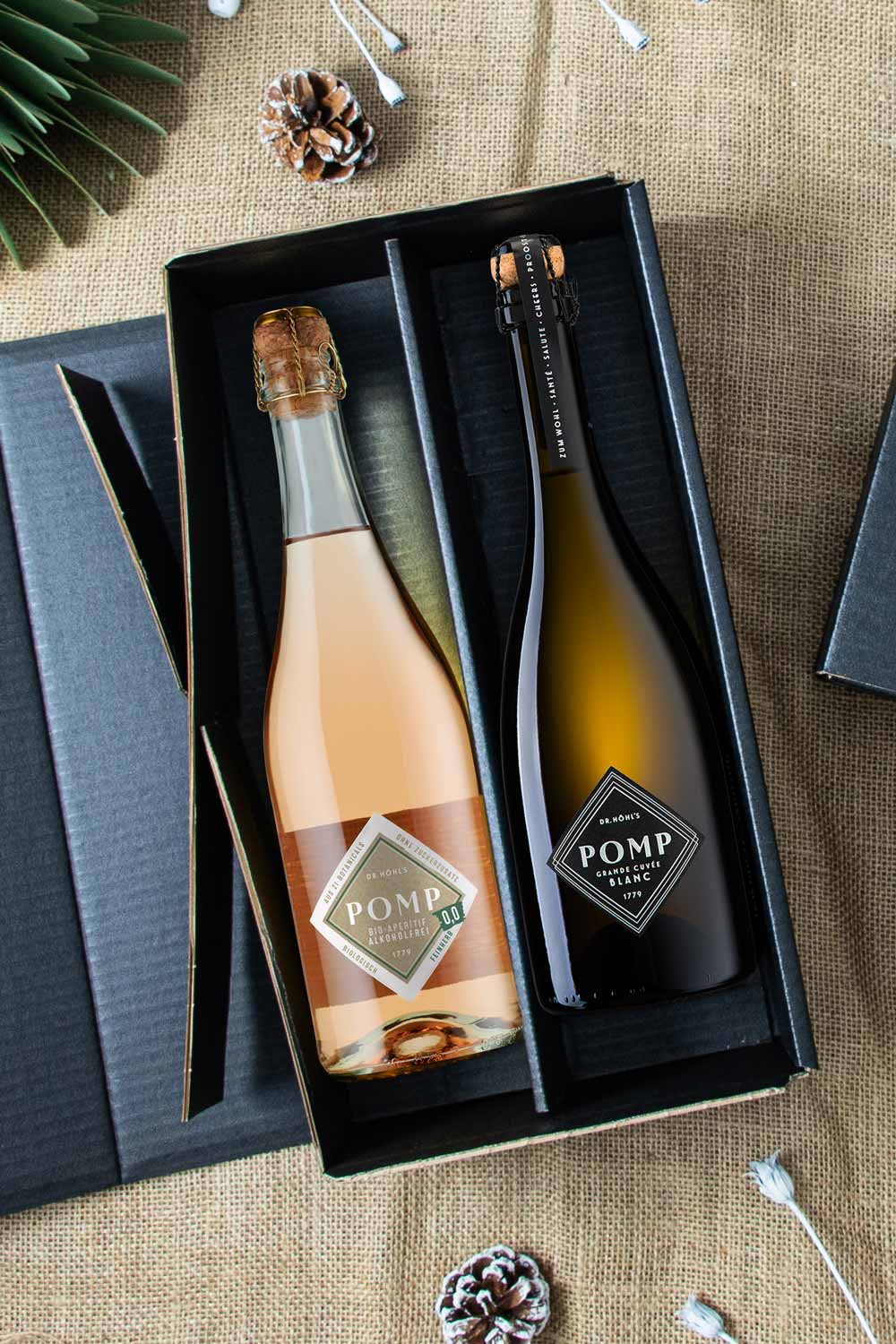 aufgeklappte schwarze präsentkartonage mit einer flasche pomp blanc sekt und eine flasche alkoholfreier sekt