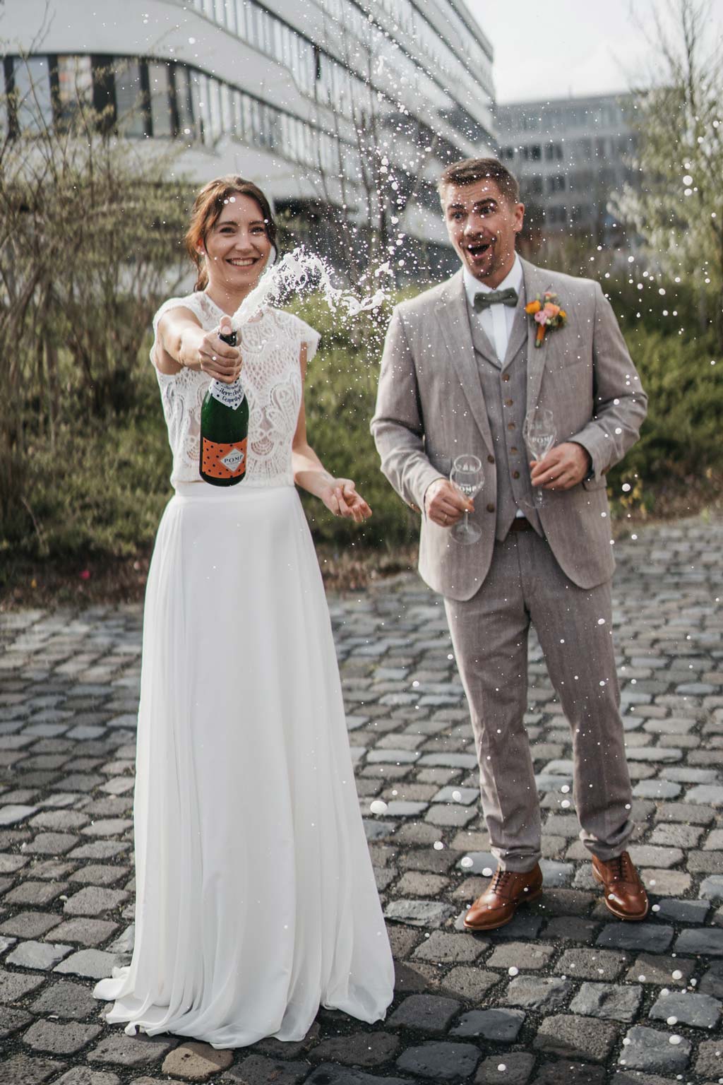 junges brautpaar lässt eine flasche pomp sekt mit orangenem etikett knallen