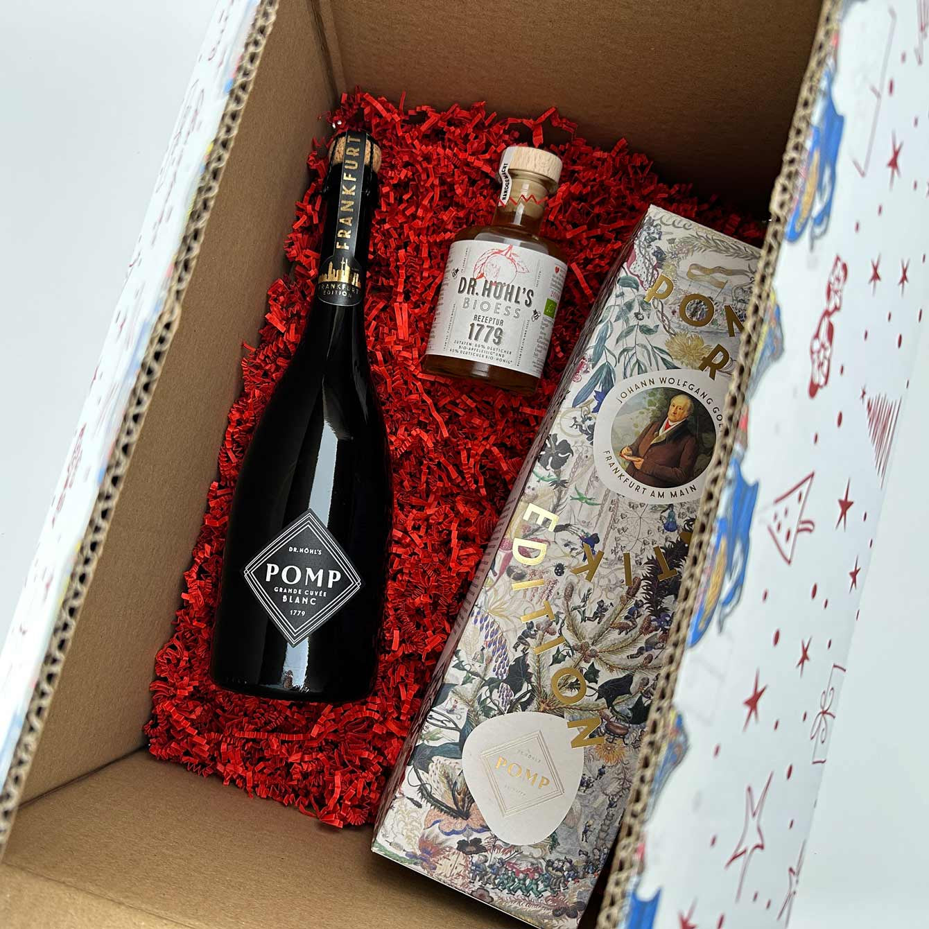 blick in eine individuell zusammengestelle weihnachtsbox mit roter sizzle pak polsterung einer flasche sekt, einer flasche essig und einer geschenkbox frankfurt