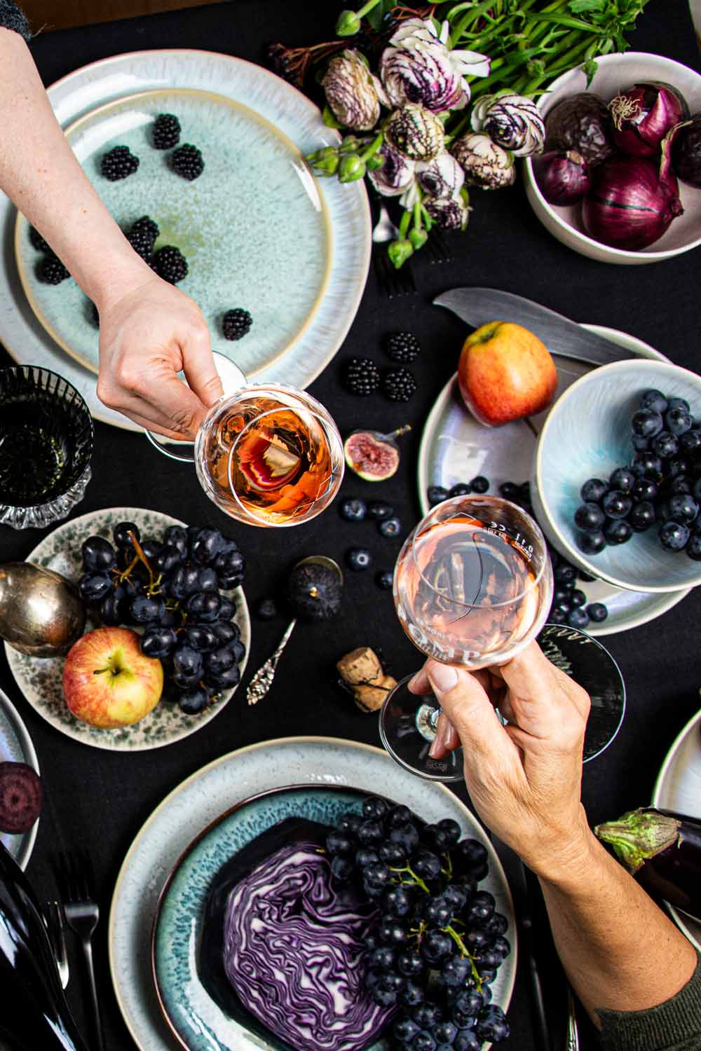 design table top shoot mit delikatessen äpfeln und trauben und zwei anstoßenden sektgläsern