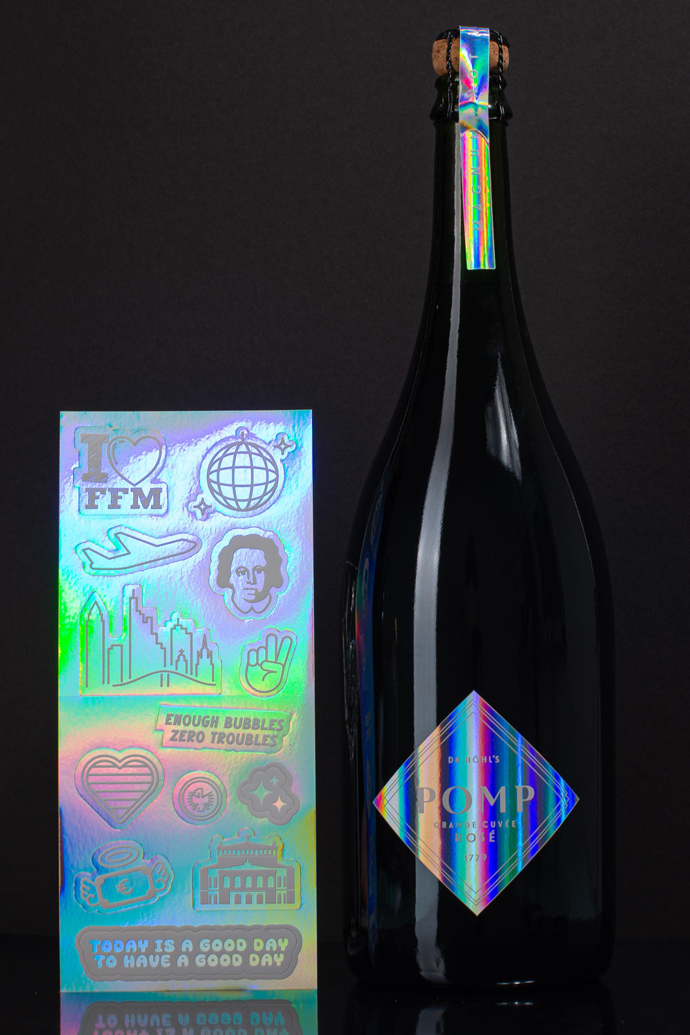 diy set aus schwarzer sektflasche mit holgrafischem etikett neben einem holgrafischen stickerbogen mit frankfurt motiven