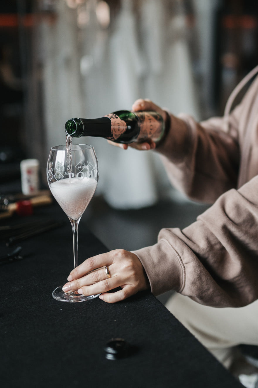 frau schenkt eine pikkolo flasche rosé in ein champagnerglas ein