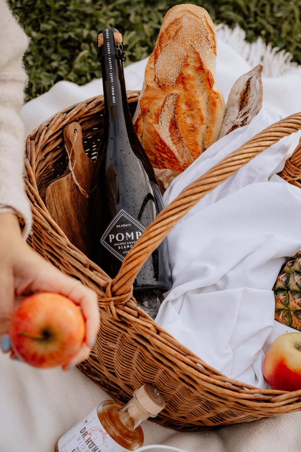 picknick korb mit einer flasche blanc sekt baguette und anderen leckereien auf einer weißen picknick decke