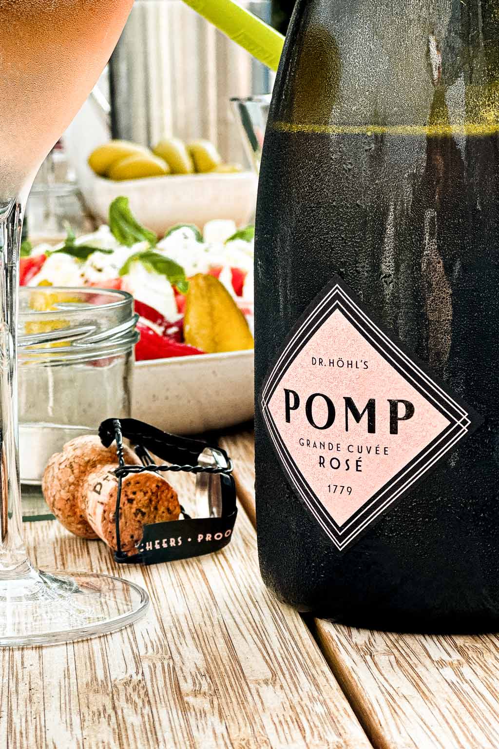 flasche pomp sekt rose steht eisgekühlt auf einem holztisch