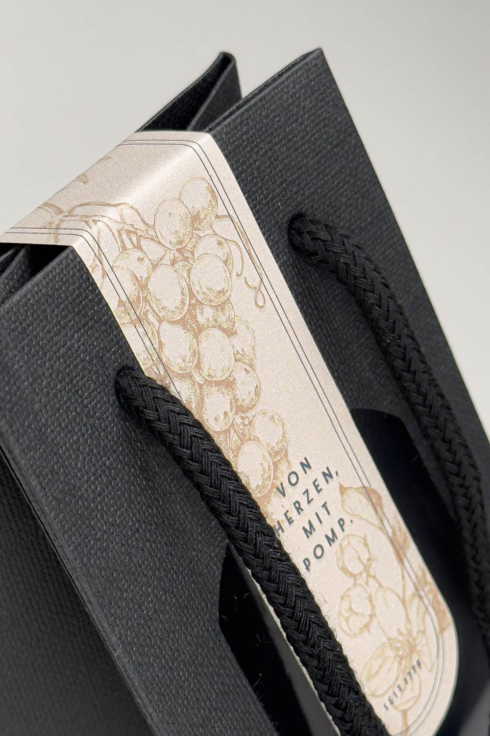 close up schwarze geschenktasche mit baumwollkordel und siegel mit partieller uv lackierung