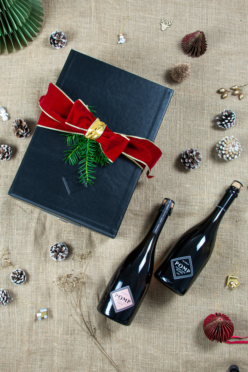 edle geschenkbox mit schleife und grünem zweig auf weihnachtlichem hintergrund