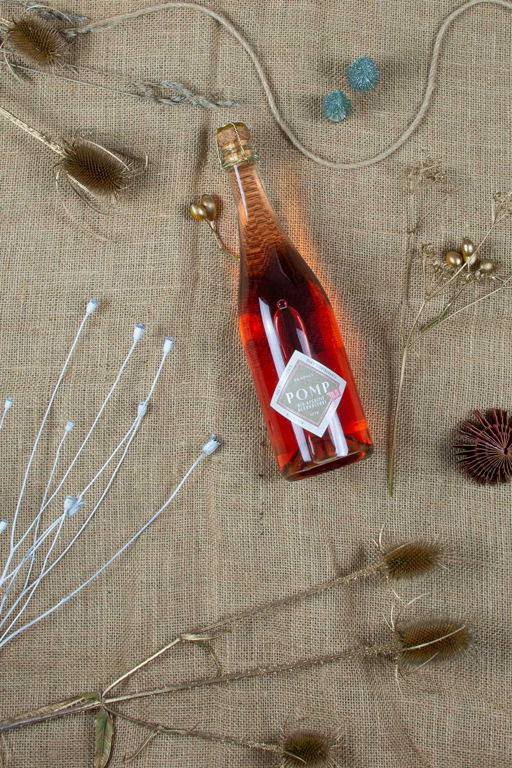 flasche bio aperitif alkoholfrei rose auf weihnachtlichem hintergrund mit trockenblumen