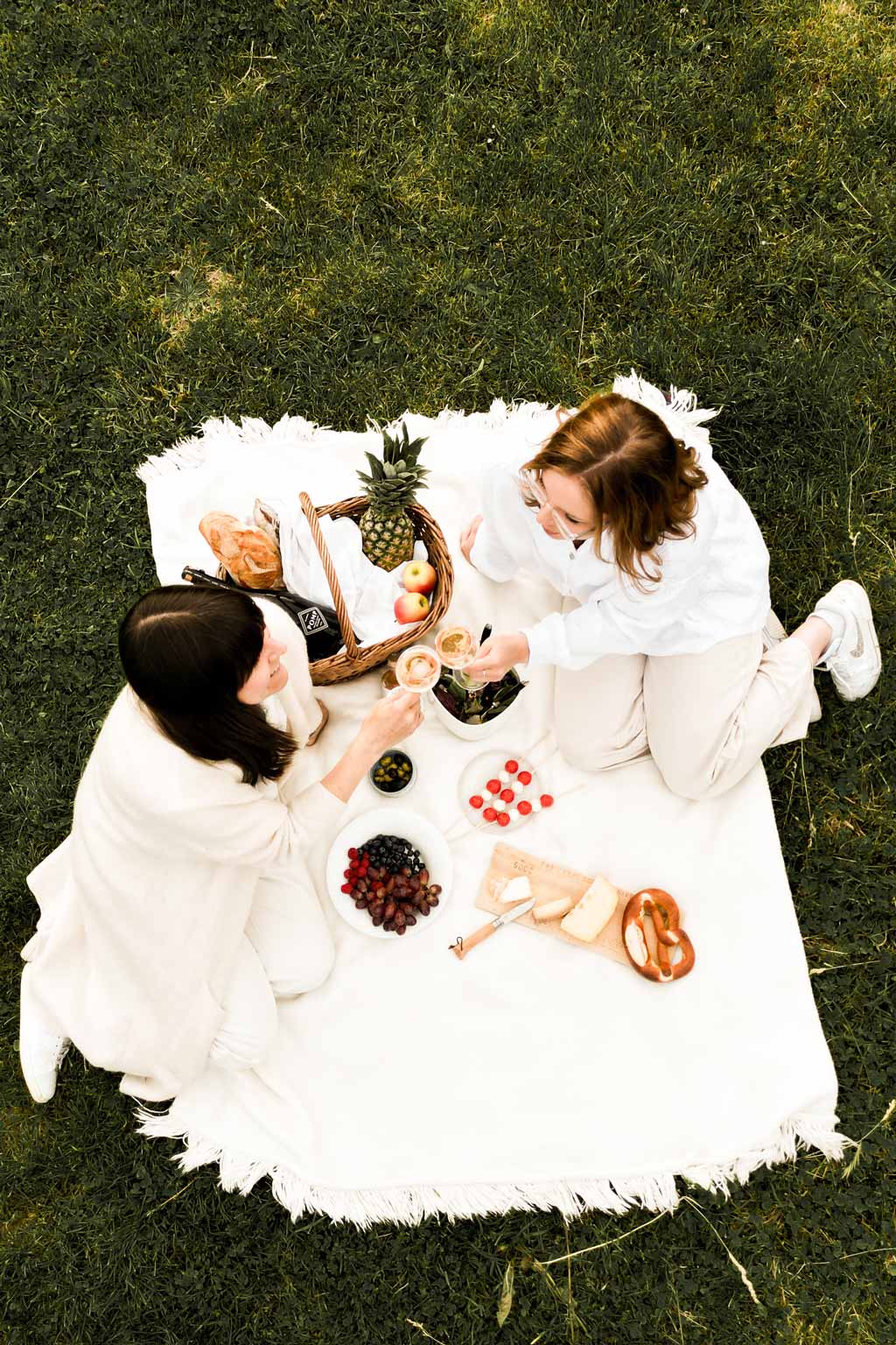 white picknick decke mit zwei personen die gerade mit sekt anstoßen von oben