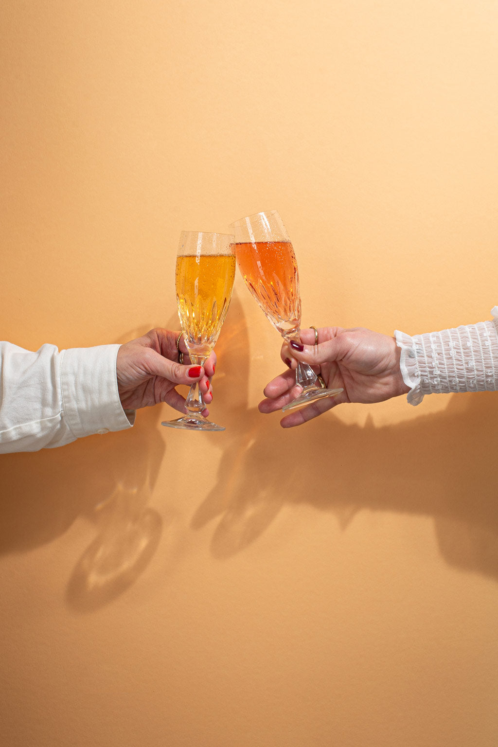 zwei hände stoßen mit kristallgläsern gefüllt mit alkoholfreiem sekt an