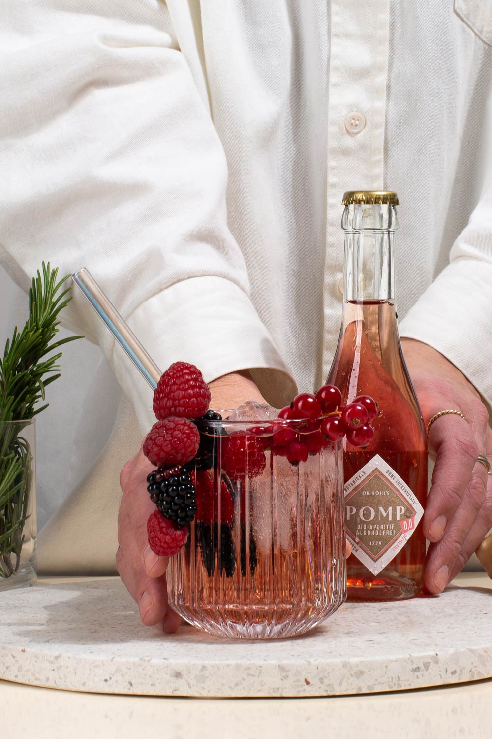 tumbler mit eiswürfeln und rose cocktail alkoholfrei mit beeren garniert