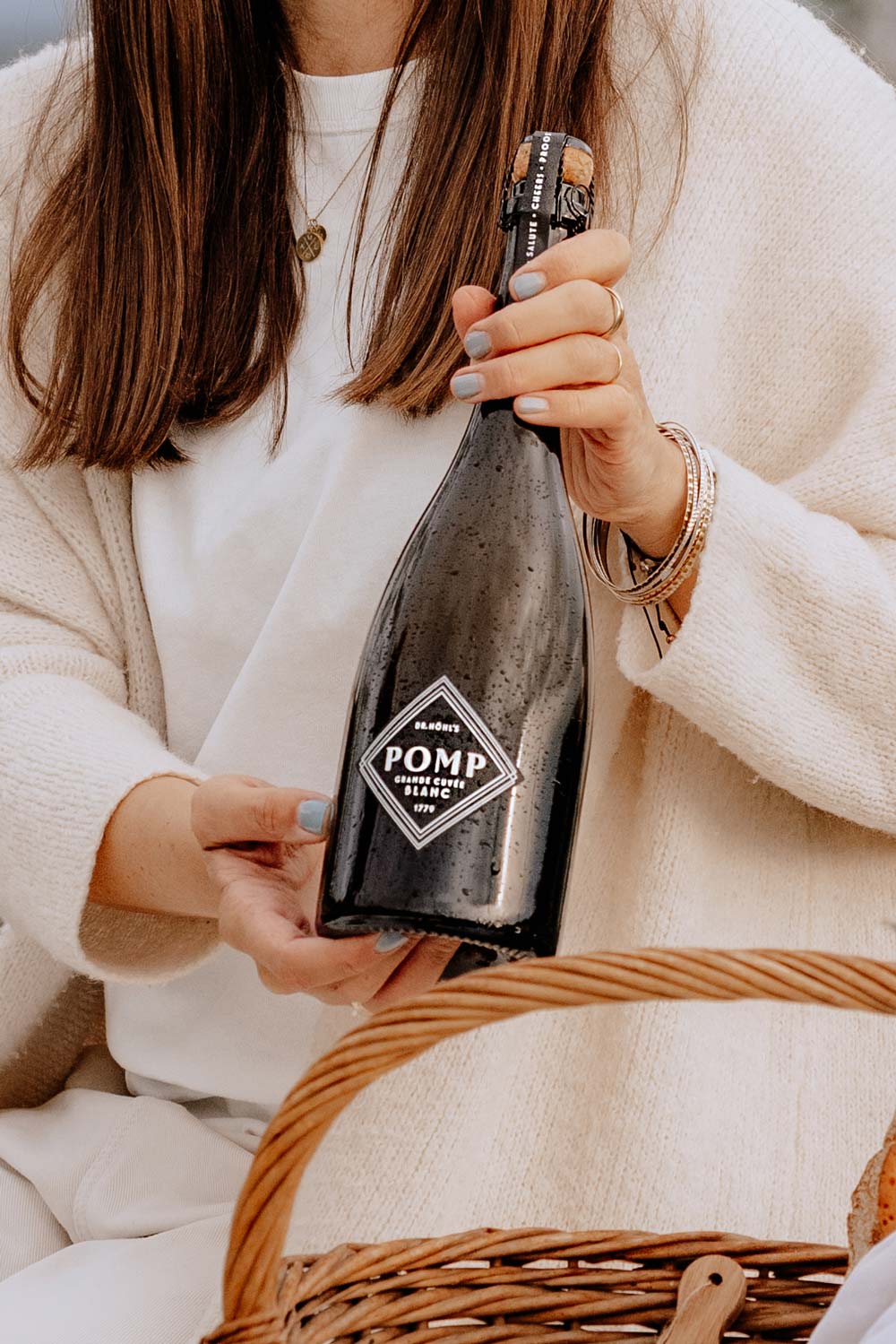 anna hält eine schwarze sektflasche pomo blanc mit schwarz-weiß etikett in die kamera