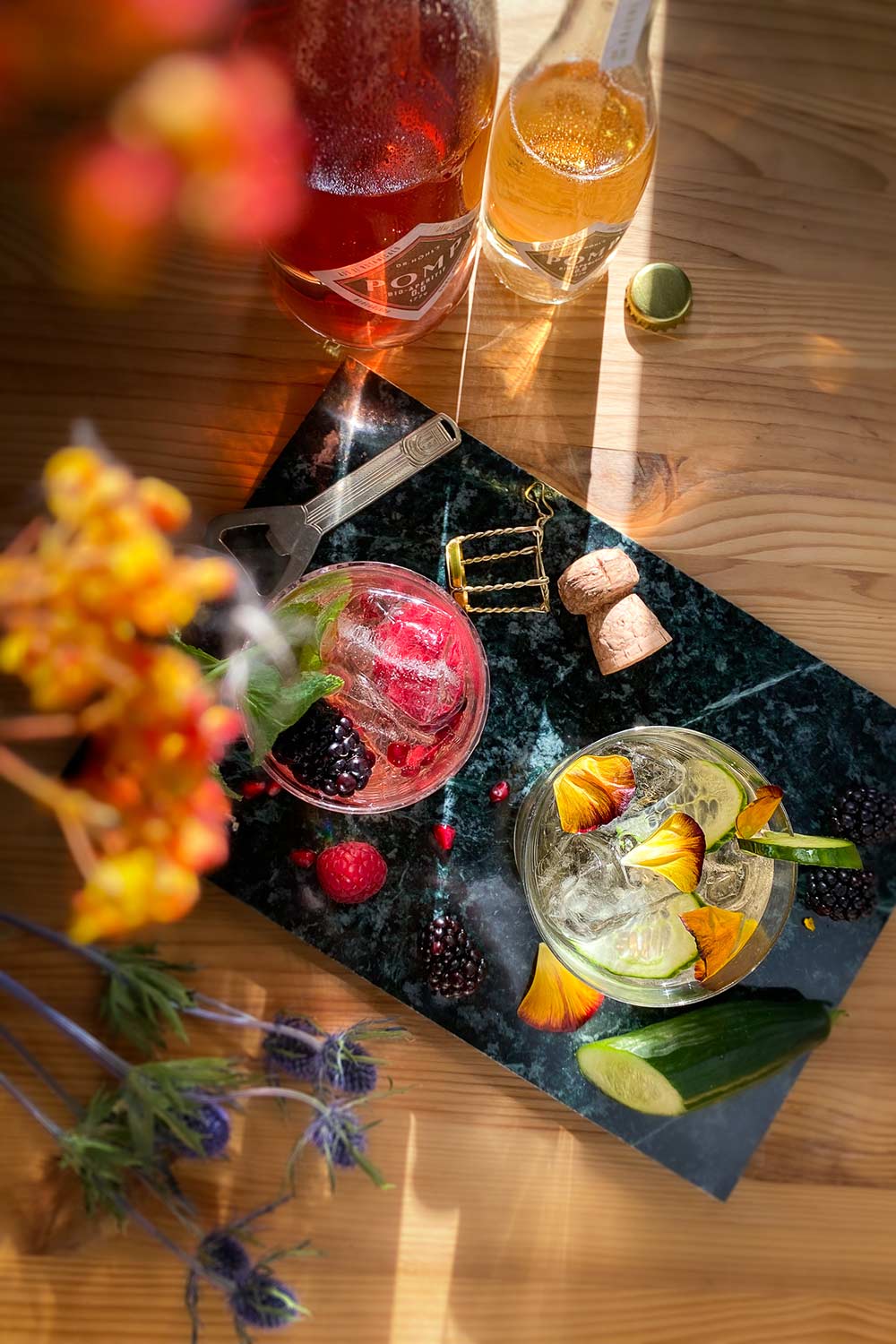 alkoholfreie drinks mit blüten und beeren dekoriert neben zwei flaschen bio filler