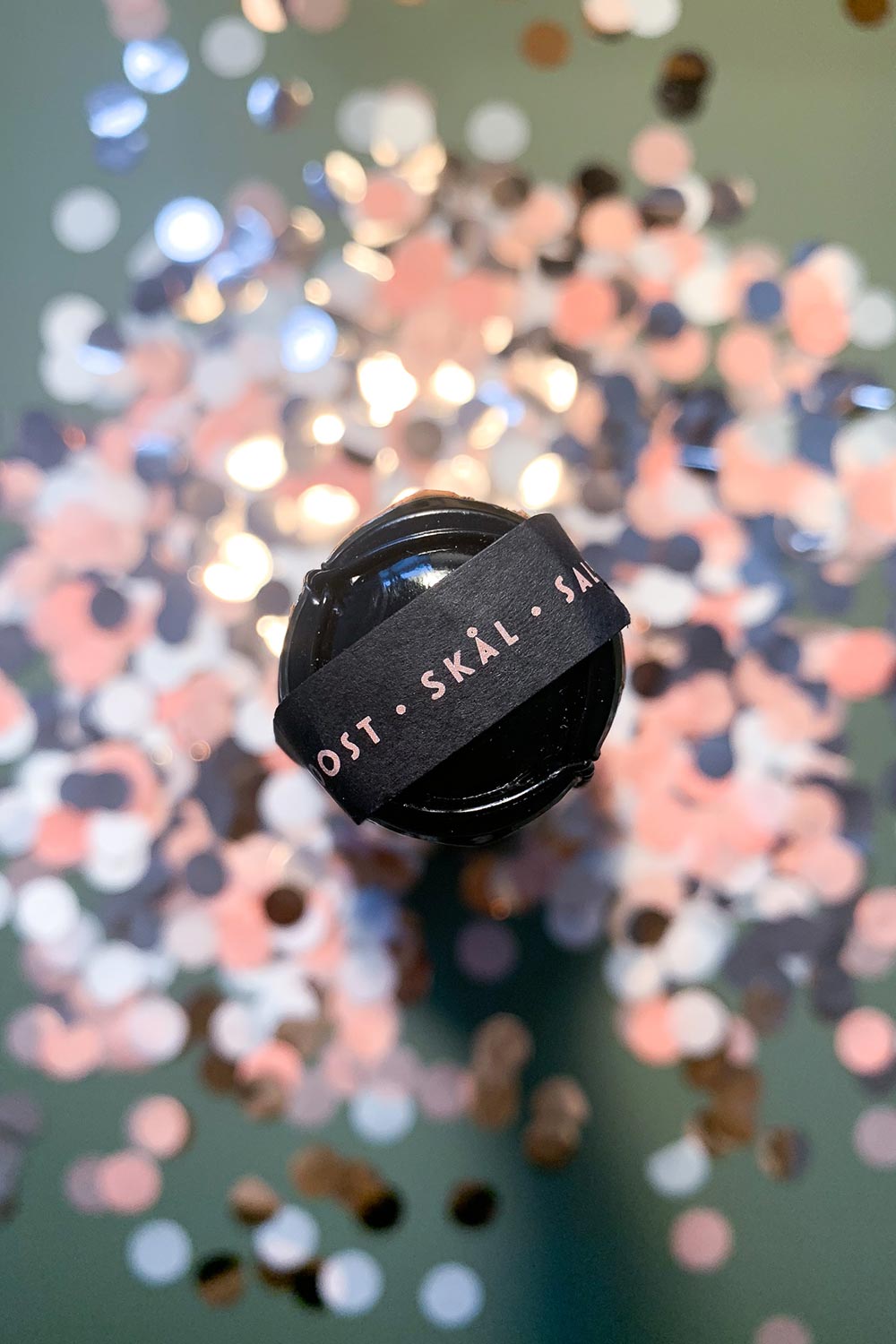 flasche sekt auf rose konfetti mit internationalem trink spruch etikett