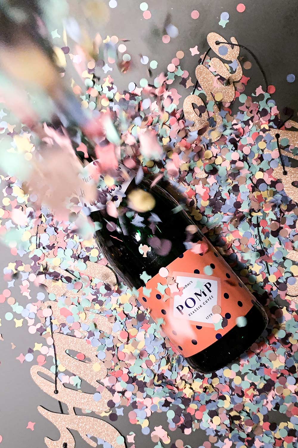 flasche design sekt mit orangenem dots etikett und konfetti