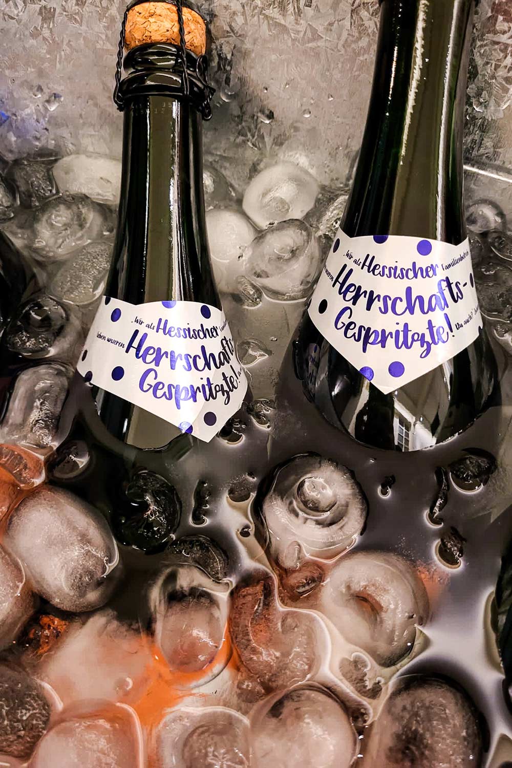 zwei flaschen sekt mit herrschaftsgespritze etikett im eiswasser