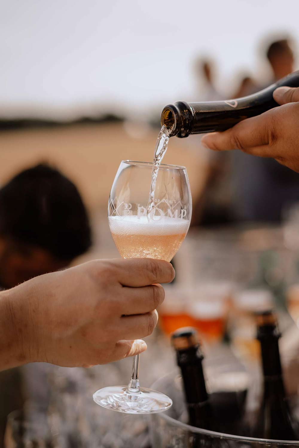 hand mit champagnerglas in das gerade rosé eingeschenkt wird