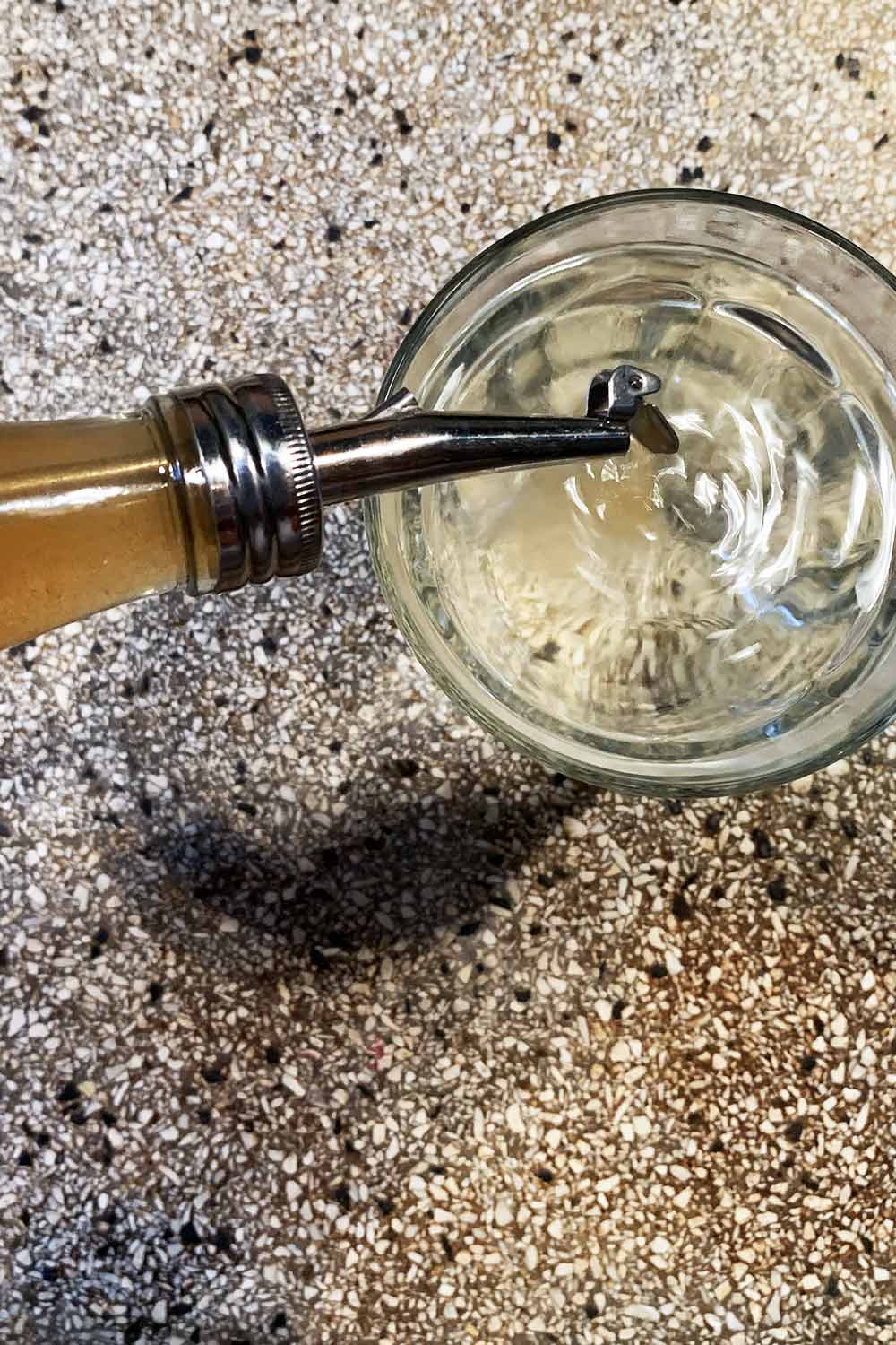 close up glas wasser in das gerade apfelessig mit einem dosierer eingegossen wird