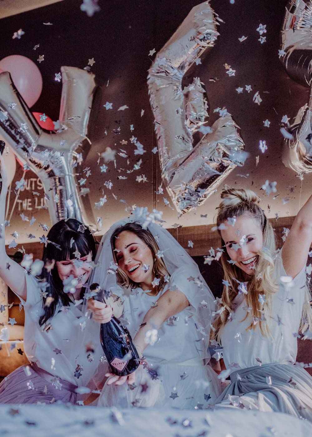 ausgelassene freundinnen feiern mit einer flasche pomp und konfetti den jga