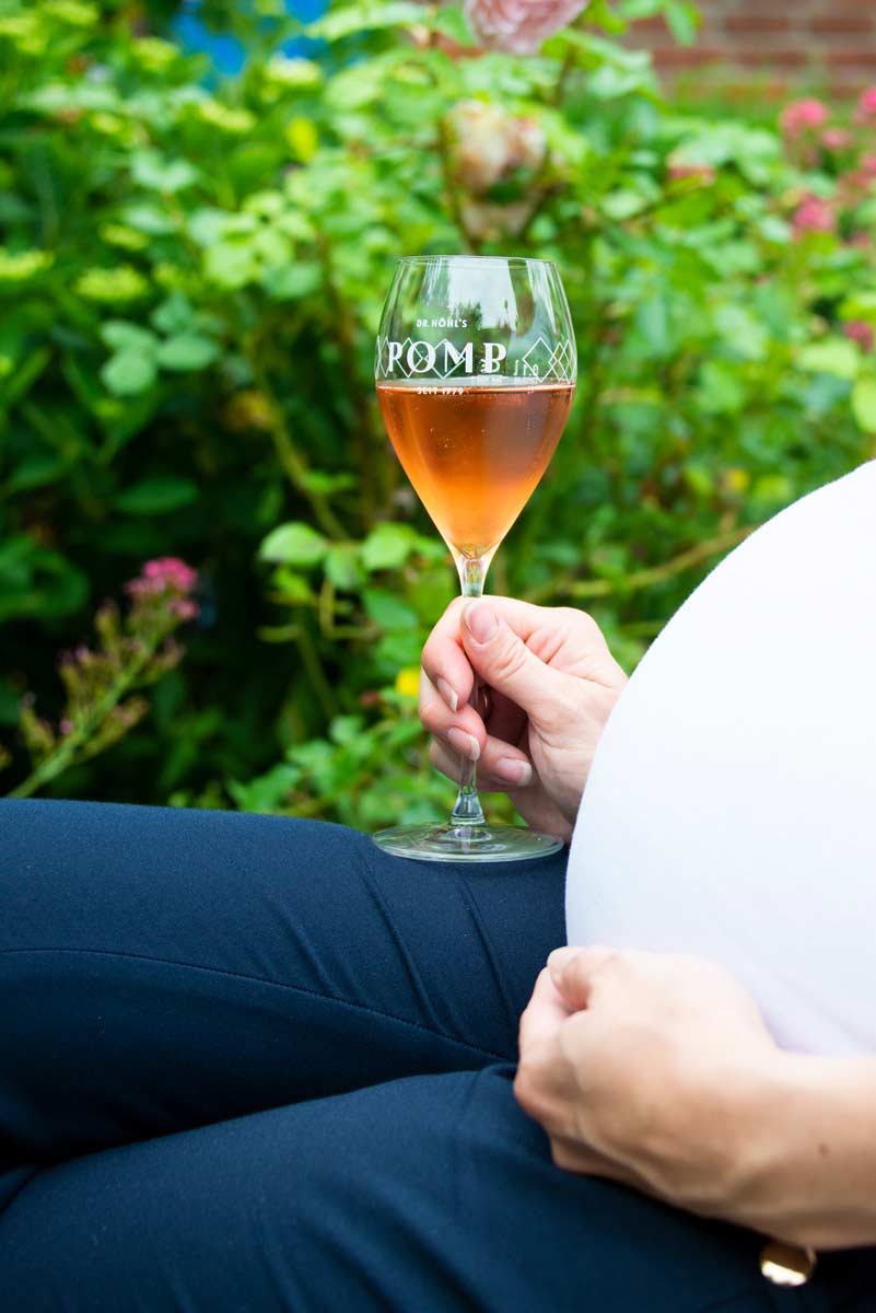 schwangere mit einem glas alkoholfreiem sekt zum anstoßen