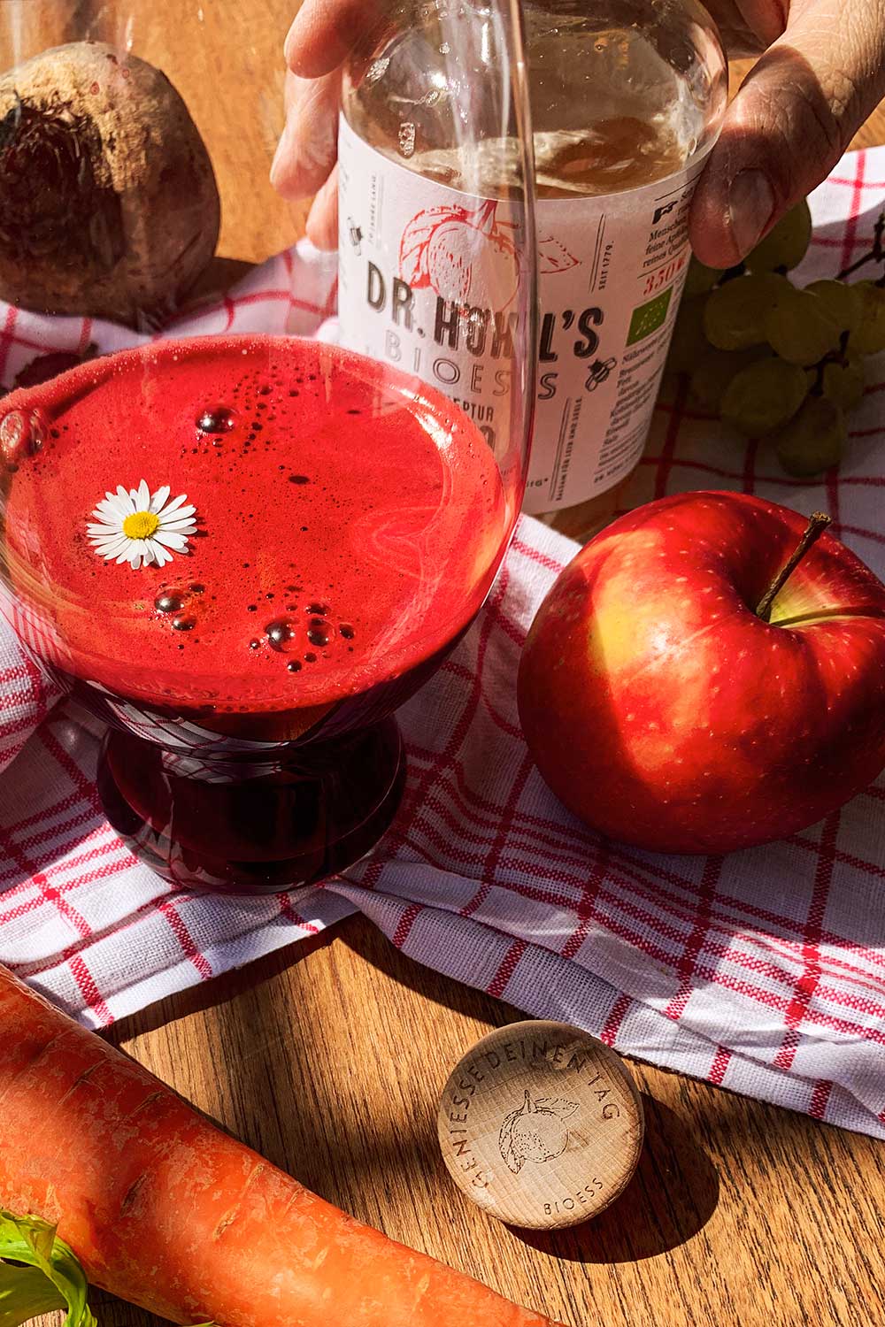 rote beete smoothie in einem glas mit gänseblümchen und apfel dekoriert