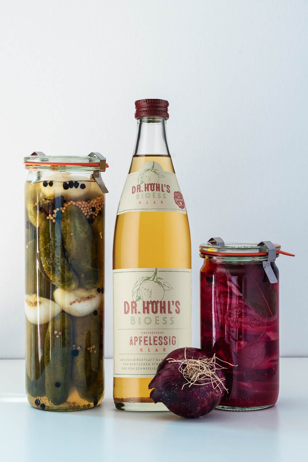 Eingelegte Gurken und pickled onions in weck gläsern mit einer flasche bio apfelessig