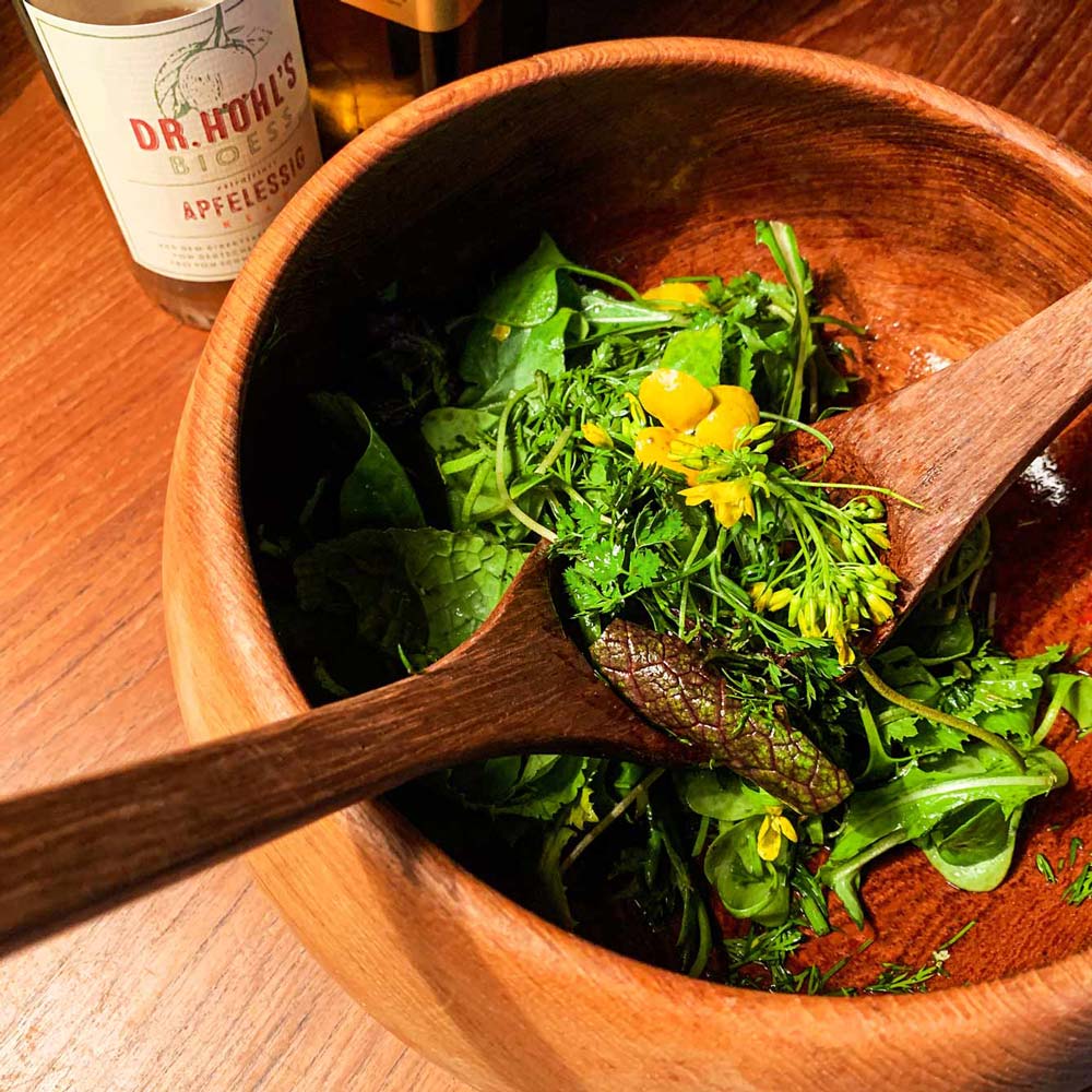 große holzschüssel mit wildkräutersalat mit blüten