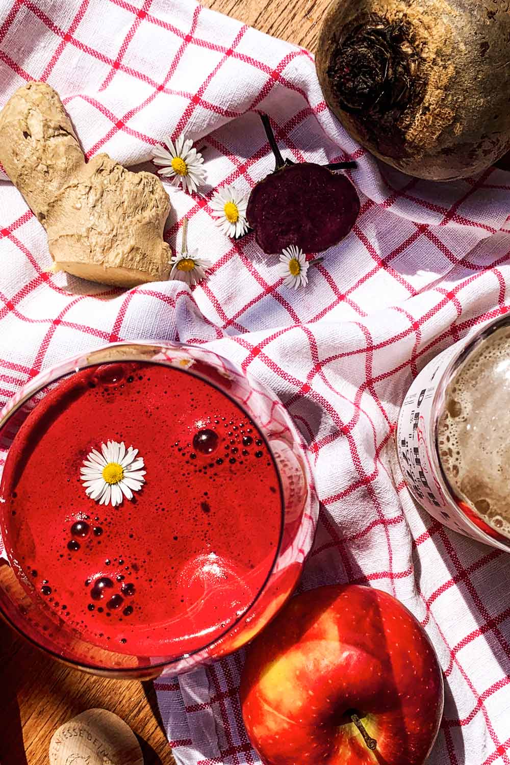 rote beete smoothie in einem glas mit gänseblümchen und apfel dekoriert